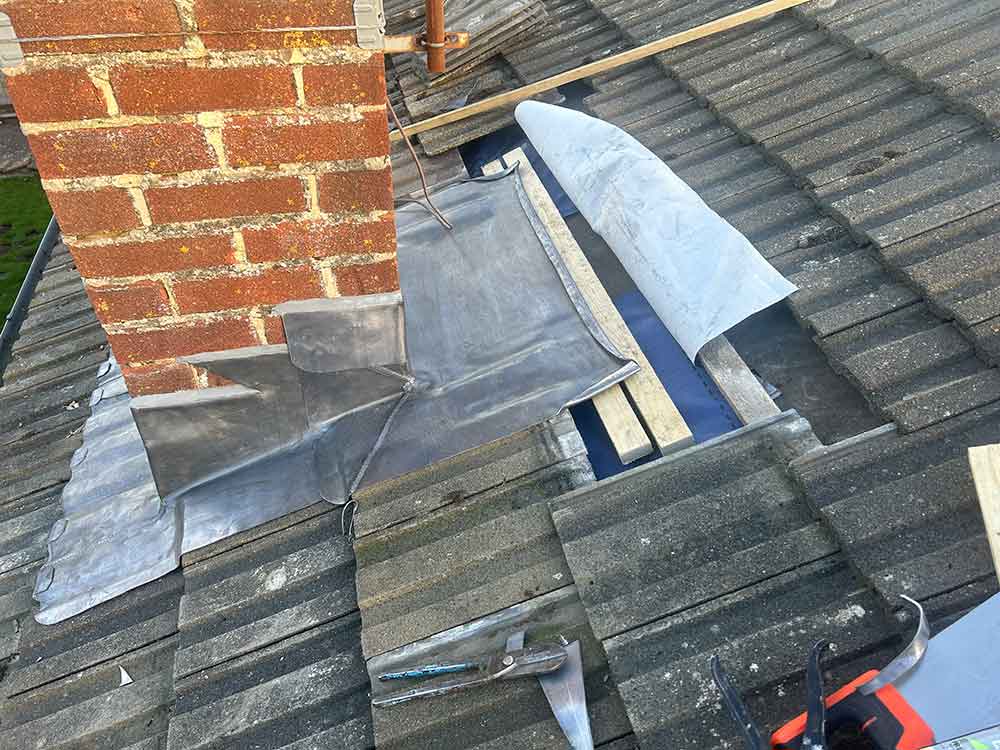 lead work neatly replaced around a chimney pot on a roof