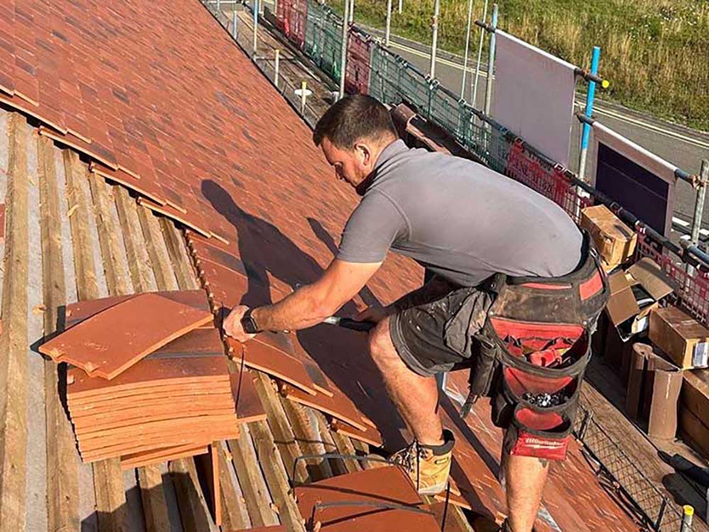 Simon Bantock replacing a roof with red tiles high on a school building